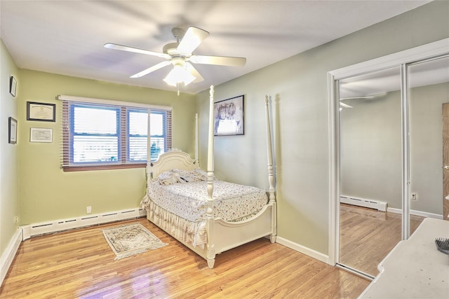 bedroom featuring a baseboard heating unit, baseboards, a closet, and light wood-style flooring