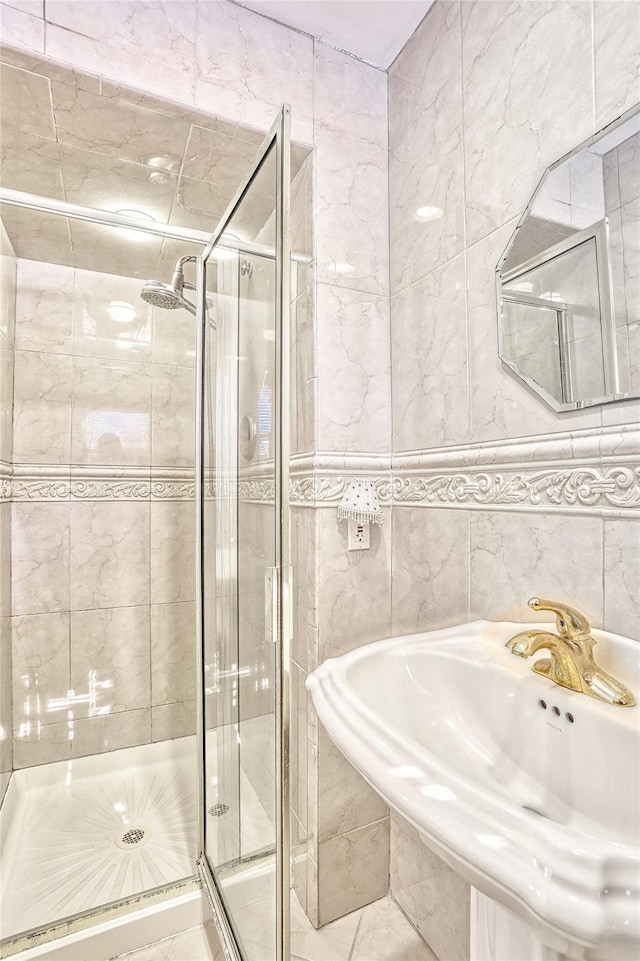 bathroom featuring a sink, tile walls, and a stall shower