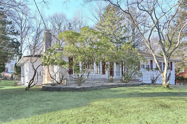 view of property hidden behind natural elements with a chimney and a front lawn