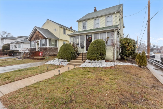 view of front of house with a sunroom and a front yard