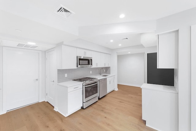 kitchen with stainless steel appliances, white cabinetry, tasteful backsplash, and light hardwood / wood-style flooring