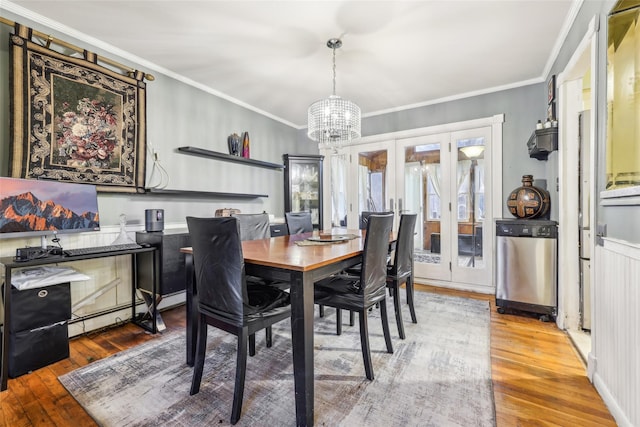 dining area with a chandelier, wood-type flooring, crown molding, and french doors