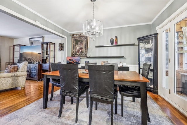 dining room with hardwood / wood-style floors, an inviting chandelier, and ornamental molding