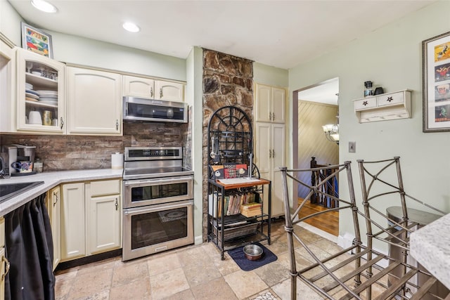 kitchen with a chandelier, sink, appliances with stainless steel finishes, and tasteful backsplash