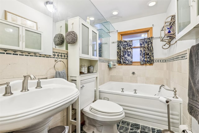 bathroom with baseboard heating, sink, tile walls, toilet, and a tub