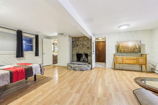 bedroom featuring beamed ceiling, a fireplace, hardwood / wood-style floors, connected bathroom, and wood walls