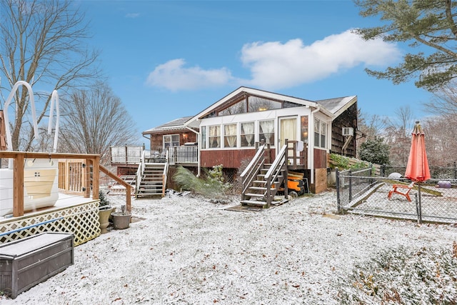 snow covered house featuring a sunroom