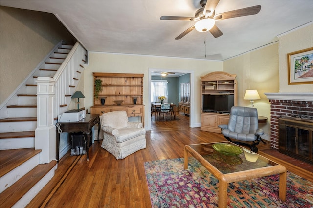 living room with a brick fireplace, ceiling fan, and hardwood / wood-style flooring