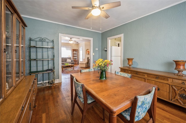 dining room with ceiling fan, dark wood-type flooring, and ornamental molding