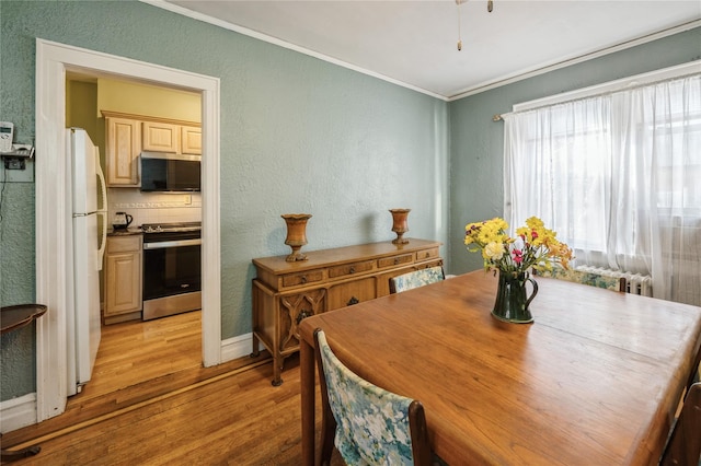 dining space with crown molding and light hardwood / wood-style flooring