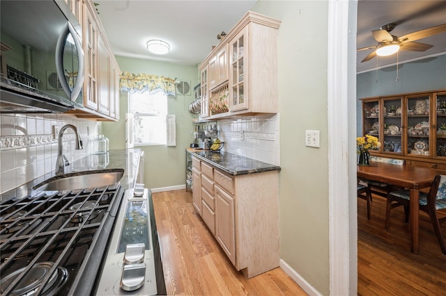 kitchen with appliances with stainless steel finishes, light wood-type flooring, backsplash, sink, and light brown cabinets