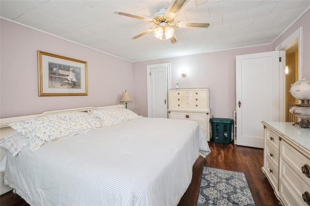 bedroom with ornamental molding, ceiling fan, and dark wood-type flooring