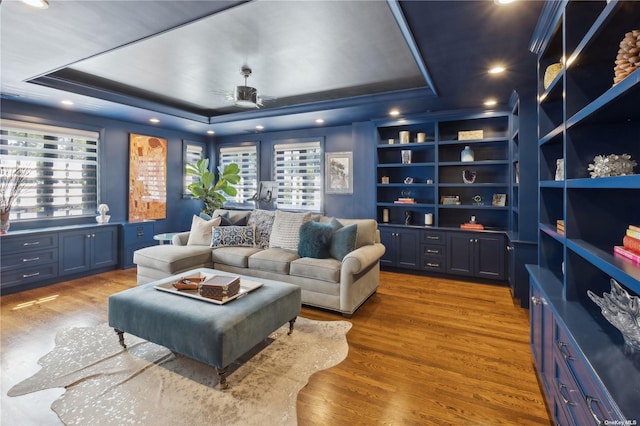 home theater with built in features, dark hardwood / wood-style flooring, and a raised ceiling