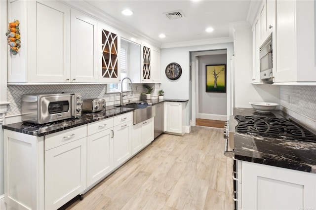 kitchen with white cabinets, backsplash, and dark stone counters