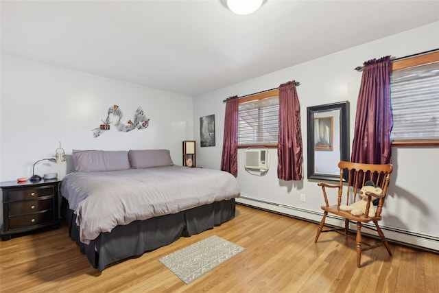 bedroom with hardwood / wood-style floors and a baseboard heating unit