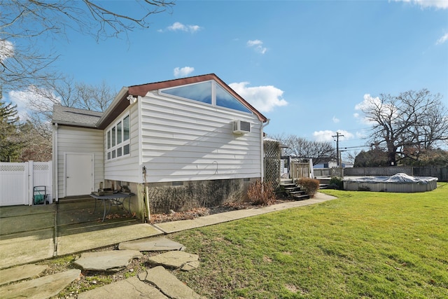 view of side of home featuring a wall mounted air conditioner, a yard, and a covered pool