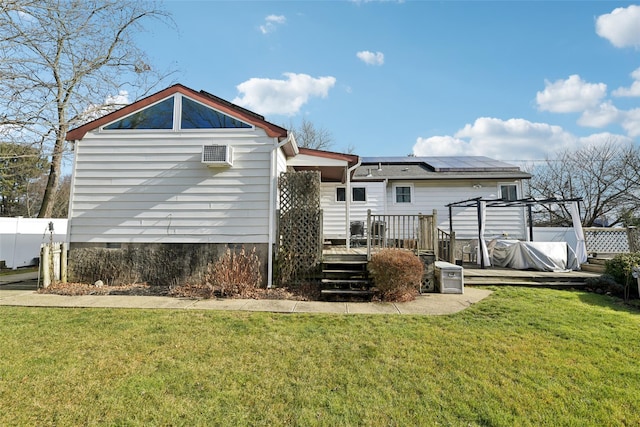 rear view of property with solar panels, a yard, and a wooden deck