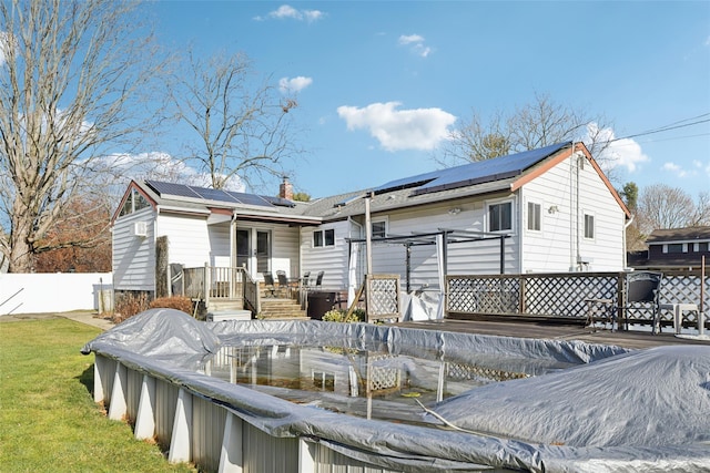 rear view of house with a deck and solar panels