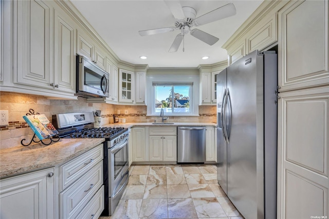 kitchen featuring crown molding, sink, ceiling fan, light stone countertops, and appliances with stainless steel finishes