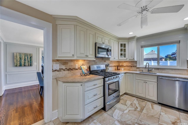 kitchen featuring sink, crown molding, ceiling fan, decorative backsplash, and stainless steel appliances