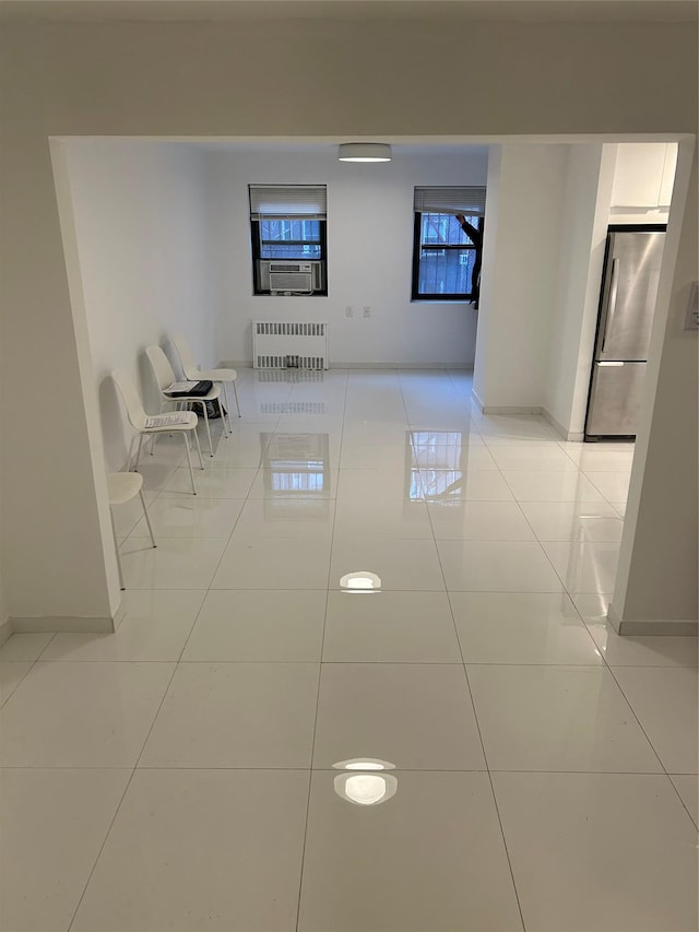 hall with radiator heating unit, plenty of natural light, and light tile patterned flooring