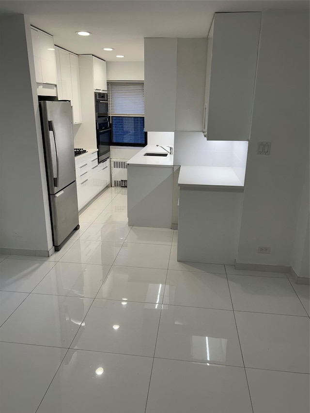 kitchen with white cabinetry, stainless steel fridge, light tile patterned floors, and double oven