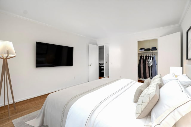 bedroom featuring hardwood / wood-style flooring, ornamental molding, and a closet