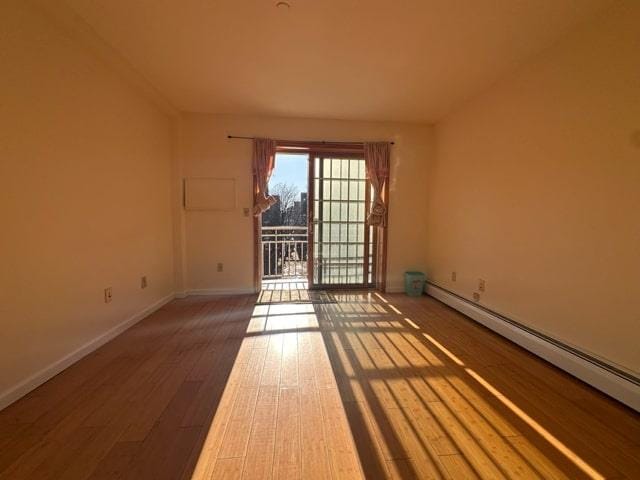 spare room with baseboard heating and hardwood / wood-style floors