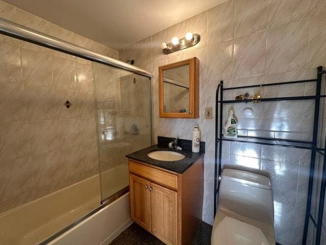 full bathroom with toilet, vanity, tile walls, and combined bath / shower with glass door