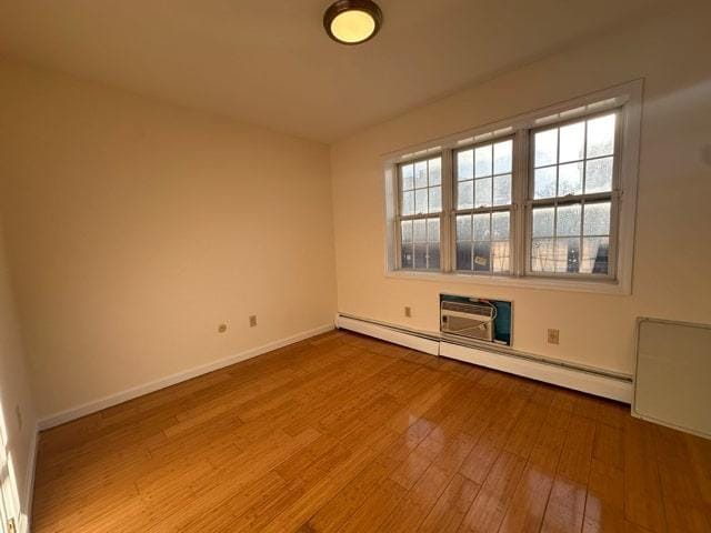 unfurnished room featuring hardwood / wood-style floors and a baseboard radiator