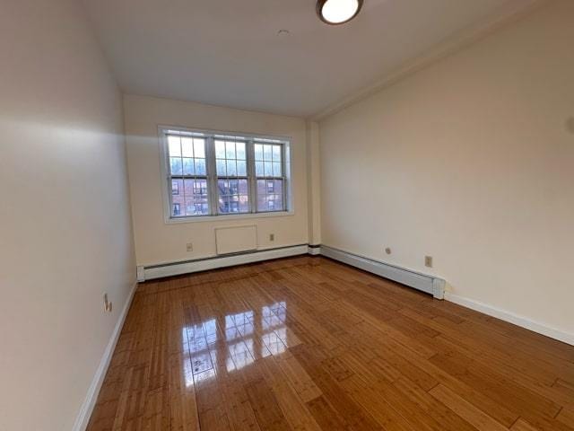 spare room featuring wood-type flooring and baseboard heating