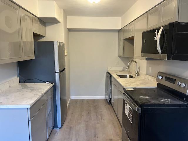 kitchen with gray cabinets, light wood-type flooring, sink, and appliances with stainless steel finishes