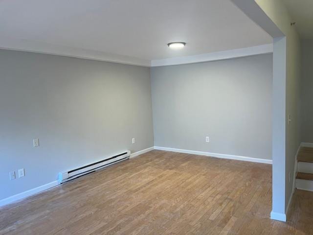 empty room with light hardwood / wood-style flooring and baseboard heating