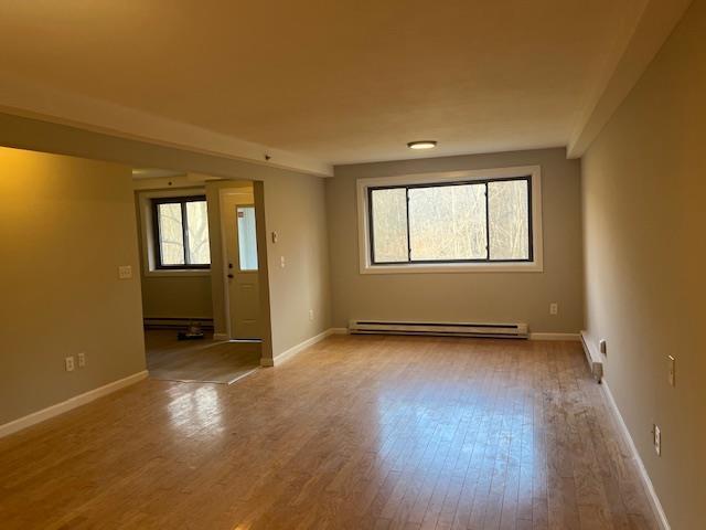 empty room with baseboard heating and light wood-type flooring