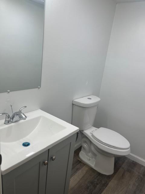 bathroom featuring wood-type flooring, vanity, and toilet