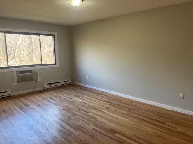 spare room with hardwood / wood-style floors, baseboard heating, and a wall mounted AC