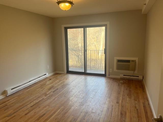 spare room featuring baseboard heating, hardwood / wood-style floors, and a wall mounted air conditioner