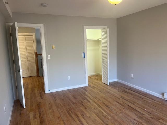 unfurnished bedroom with a walk in closet, dark wood-type flooring, and a closet