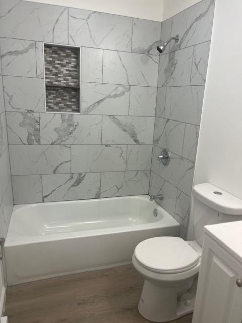 full bathroom with hardwood / wood-style floors, vanity, tiled shower / bath combo, and toilet