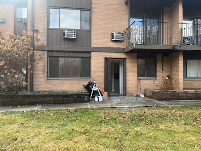 back of house featuring a balcony, a yard, a patio, and a wall mounted AC