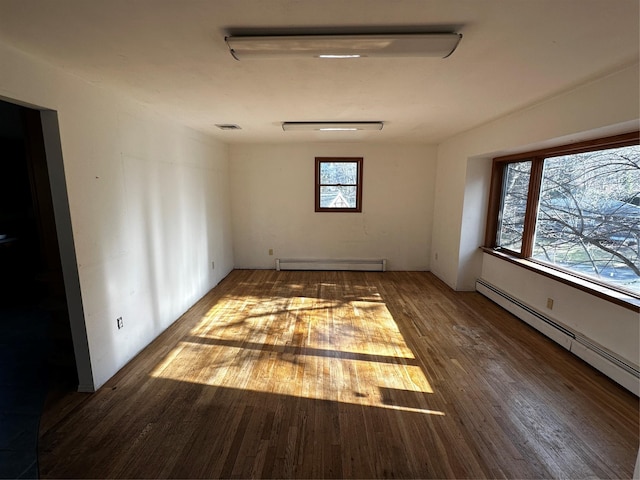 unfurnished room featuring dark hardwood / wood-style floors and a baseboard heating unit