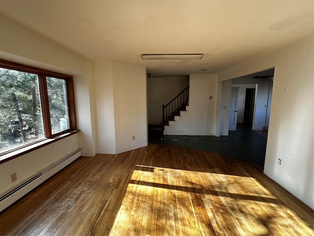 empty room with wood-type flooring and a baseboard heating unit