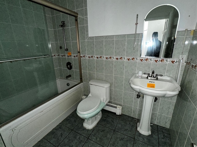 bathroom featuring combined bath / shower with glass door, toilet, tile walls, and a baseboard heating unit