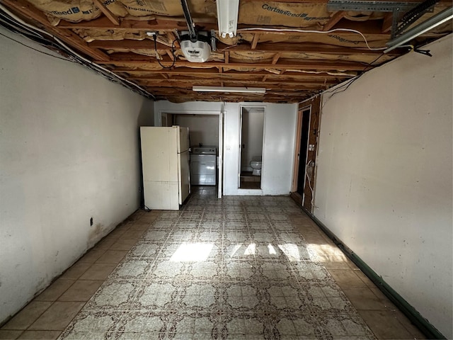 basement featuring washer / dryer and white refrigerator