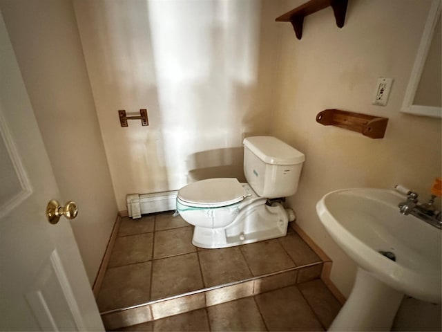 bathroom featuring tile patterned flooring, toilet, a baseboard heating unit, and sink