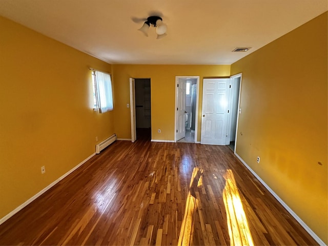 unfurnished bedroom with dark hardwood / wood-style floors and baseboard heating