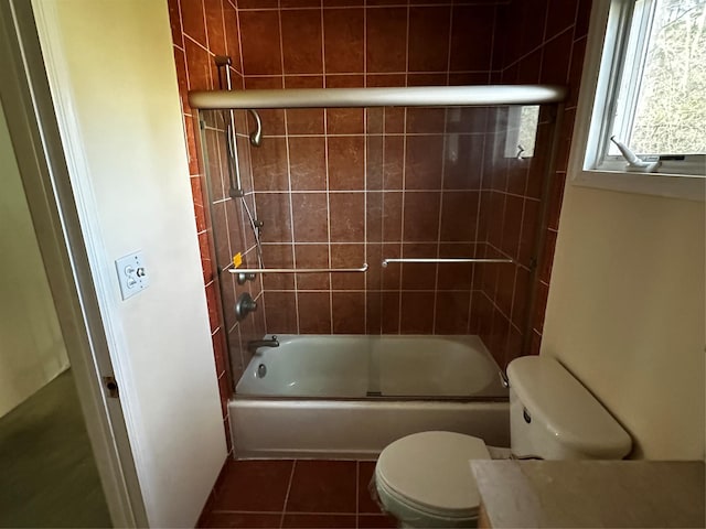 bathroom with tile patterned flooring, bath / shower combo with glass door, and toilet