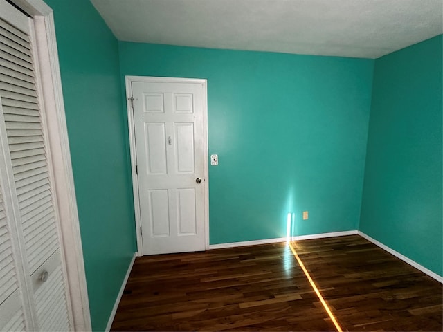 unfurnished bedroom featuring a closet and dark wood-type flooring