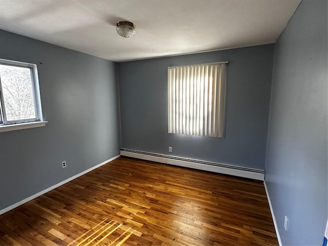 empty room featuring baseboard heating and dark wood-type flooring