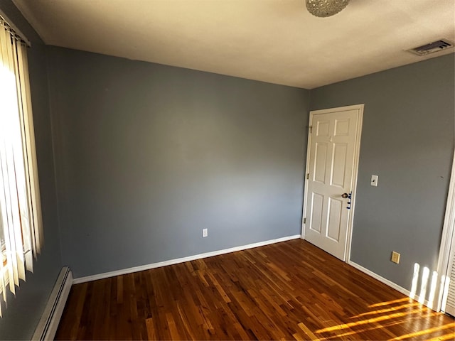 empty room featuring dark wood-type flooring and a baseboard radiator